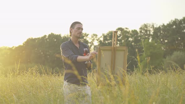 Concentrated Caucasian Man Painting Landscape at Sunset. Portrait of Inspired Male Painter with alt
