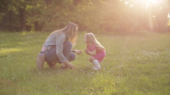 Little Kid with Long Hair Sitting on Front of Her Mother