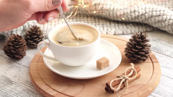 Woman's Hand Stirring Sugar Cube in Cup of Coffee with Spoon