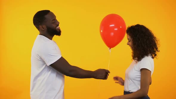 Smiling Afro-American Man Presenting Balloon to Cute Woman, Birthday Gift, Date alt