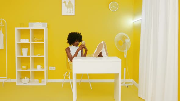 Black Woman Is Relaxing In Office Using Smartphone alt