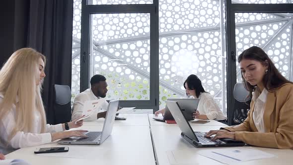 Coworkers Studying Different Business Papers and Working with Computers in the Modern Office alt