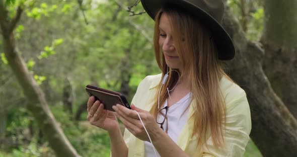 Young traveling woman watching a live stream on her smartphone in the nature. alt