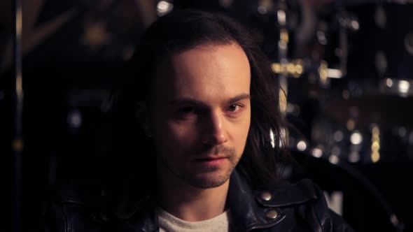 Brutal Man with Bristles on His Face Looking at the Camera. Long Dark Hair