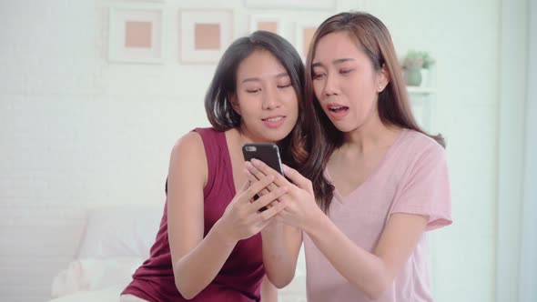 Young Asian women lesbian using smartphone checking social media in bedroom. alt