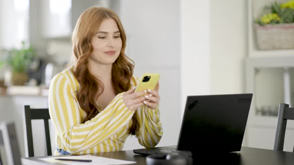 Young woman with smartphone and laptop working from home