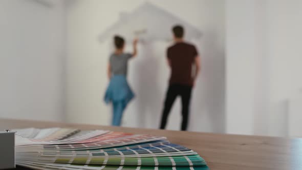 Blurred couple in the background painting wall in the house. Shot with RED helium camera in 8K. alt