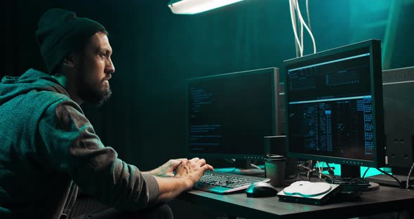 Male Hacker Using Keyboard to Type a Dangerous Malware Into Bank System Hacker Breaks Into alt