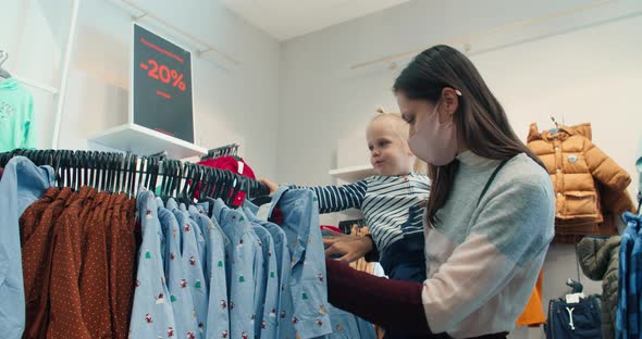 Young beautiful woman with daughter shopping with discounts closing new clothes alt