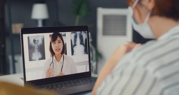 Asia girl wear protective face mask using laptop talk about disease in video call with senior doctor