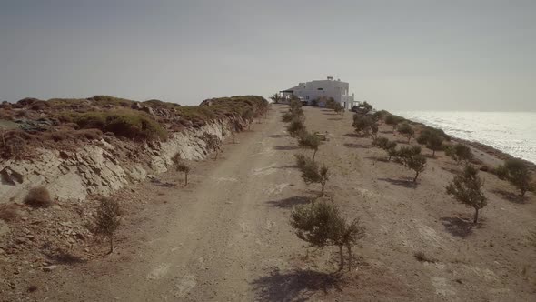 Aerial view of a dirt road with a big house on the sea, Greece. alt