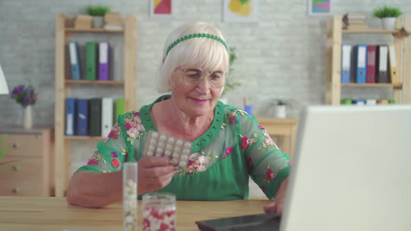 Pensioner Is Looking for Information on the Internet About the Pills Sitting at the Table alt