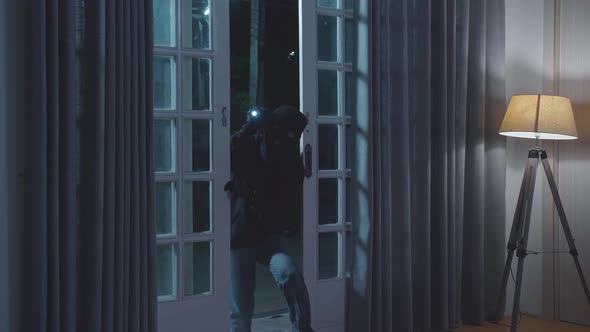 Thief Man Holding Flashlight Opening The Door And Entering Someone's House alt
