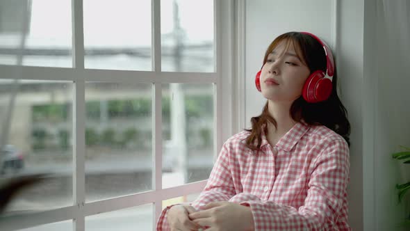 Asian girl sitting lonely listening to music in the window, lifestyle concept, social distancing