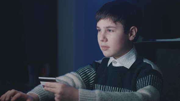 12-13 Year Old Boy Using Computer Laptop and Shopping Online with Credit Card While Sitting at Home alt