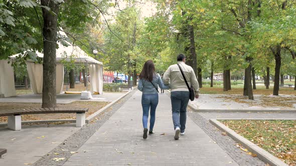 Autumn Cloudy Day City Park Man Woman Holding Hands Go Along Path View From Back alt
