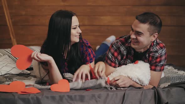 enamored man and woman are throwing into each other hearts by handmade on the bed alt