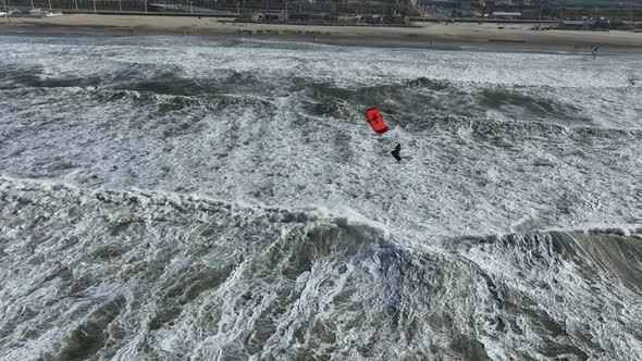 Kite surfer catching large air in murky storm water waves at Scheveningen; drone alt