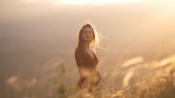 Young Romantic Woman in a Red Dress Walks Across the Field at Sunset alt