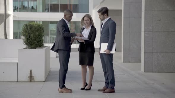 Business Partners Studying Documents Outdoors, alt