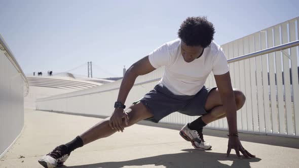 Concentrated African American Man Stretching Legs on Bridge alt