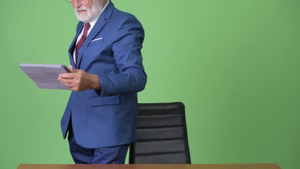 Handsome Senior Bearded Businessman Against Green Background alt