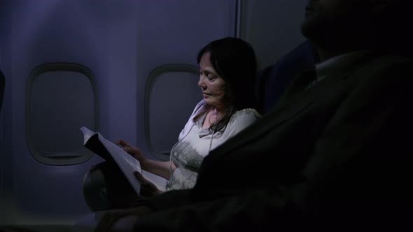 Woman reading at night on airplane flight