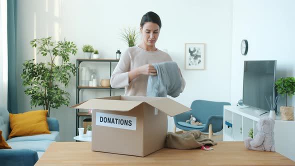 Mother Packing Donation Box While Father and Daughter Bringing Clothes for Charity at Home alt