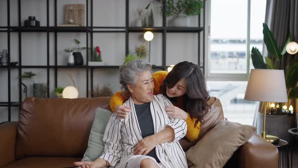 Asian daughter surprises her mature mother with a hug behind her back