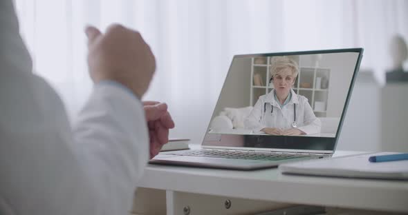 Woman Doctor Is Lecturing at Screen of Laptop, Male Physician Is Arguing with She and Gesticulating alt