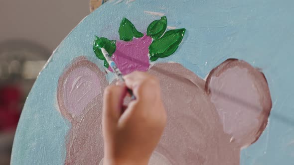 Close Up View of Little Girl's Hand Painting Leafs Teddy Bear with Paintbrush