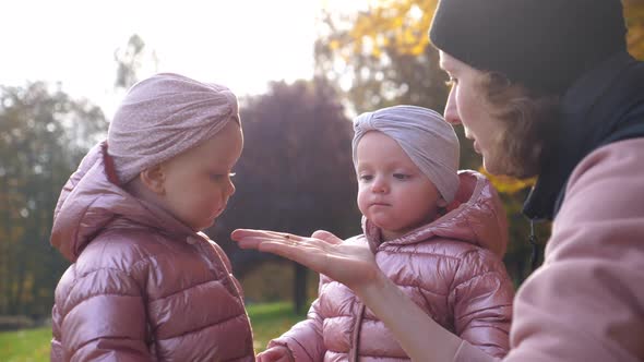 Two Curious Girls Look at Insect on Mother's Hand Spending Quality Time in Nature alt