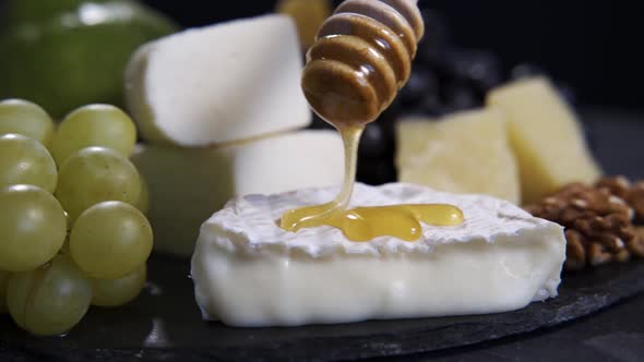 The Chef Pours Honey on the Camembert Cheese Using a Honey Spoon