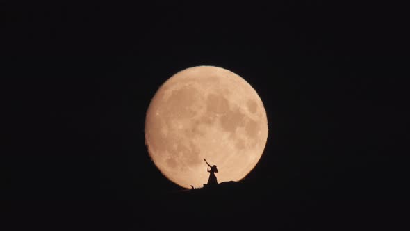 Silhouette of Dancing Woman at Huge Moon Background at Night
