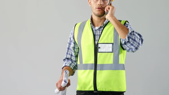 Male architect holding blue print and talking on mobile phone 4K 4k alt