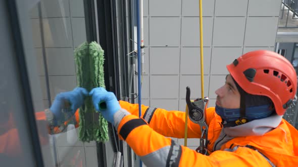 Equipped Industrial Climber Washes Windows with a Fur Coat at High Building, Slow Motion alt