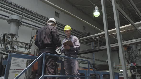 Factory workers discussing with each other in factory