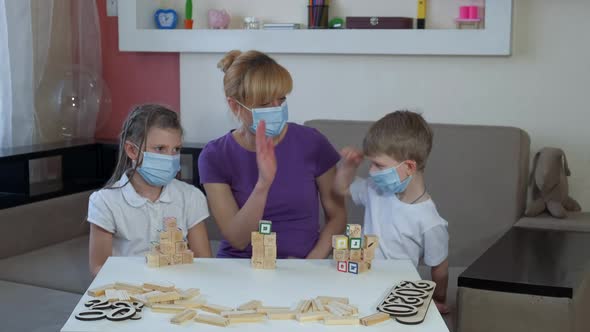 Mother Son and Daughter in Medical Masks Play Wooden Puzzles in the Room