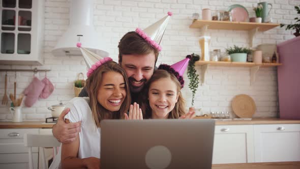 Happy Family with a Daughter Celebrating Birthday in Kitchen Using Laptop for a Video Call During alt