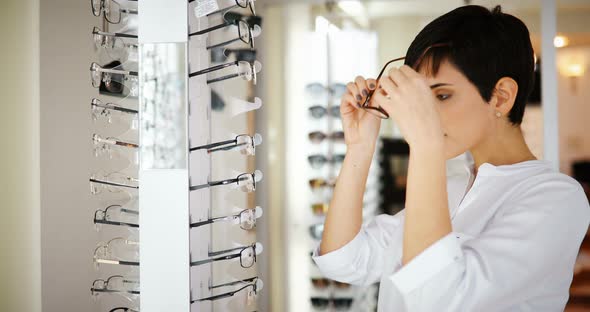 Health Care Eyesight and Vision Concept  Happy Woman Choosing Glasses at Optics Store