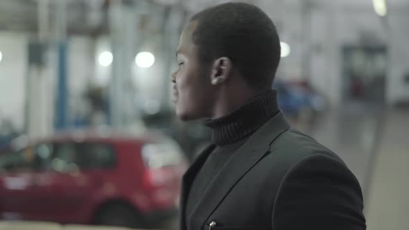 Portrait of Attractive African American Guy Looking Back at New Cars and Turning To Camera alt