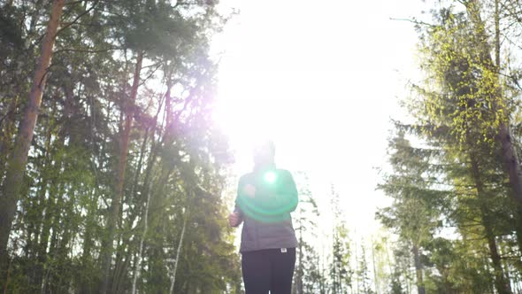 Asian woman wearing coat and going jogging in the forest to see a beautiful nature in the morning alt