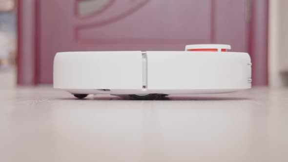 Robot vacuum cleaner vacuuming the floor in the room. Smart home with automated devices alt
