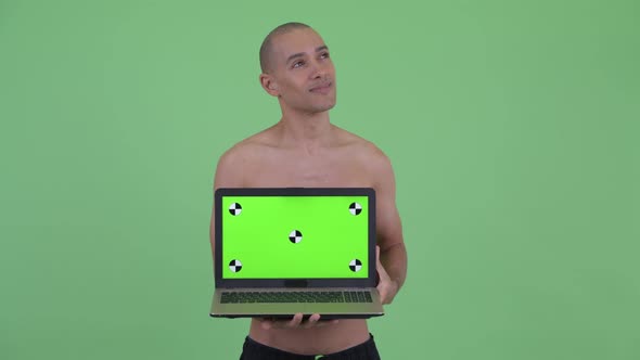 Happy Bald Multi Ethnic Shirtless Man Thinking While Showing Laptop alt