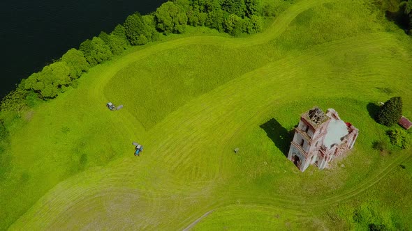 Mowing Grass Near the Church in the Middle of the Lake