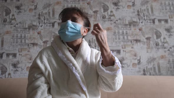 Elderly Woman Takes Off Face Mask Sitting on Sofa at Home When End of Operation Quarantine and