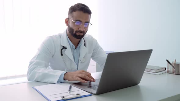 Serious Indian Latin Doctor in Hospital Clinic Working Using Laptop Computer alt