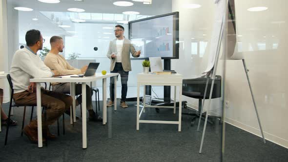 Employee Reporting About Sales Results Talking To Staff in Boardroom Using Digital Screen alt