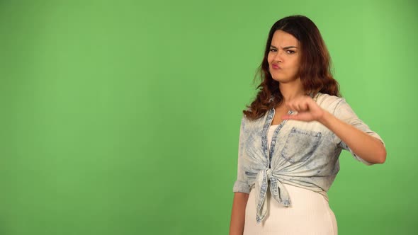 A Young Beautiful Caucasian Woman Shows a Thumb Down to the Camera  Green Screen Background