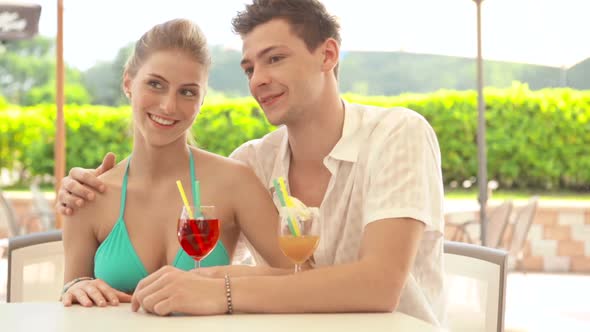 A Young Couple at Water Park in Summer Day is Drinking Cocktail at Bar Dolly alt
